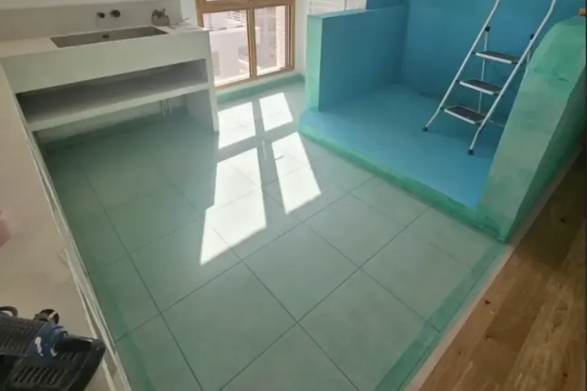 La même pièce en cours de chantier : étanchéité appliquée et carrelage fraîchement posé